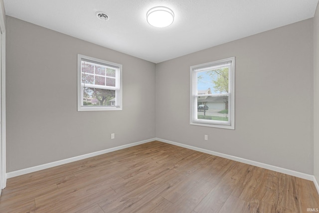 empty room with baseboards, light wood-style floors, and visible vents