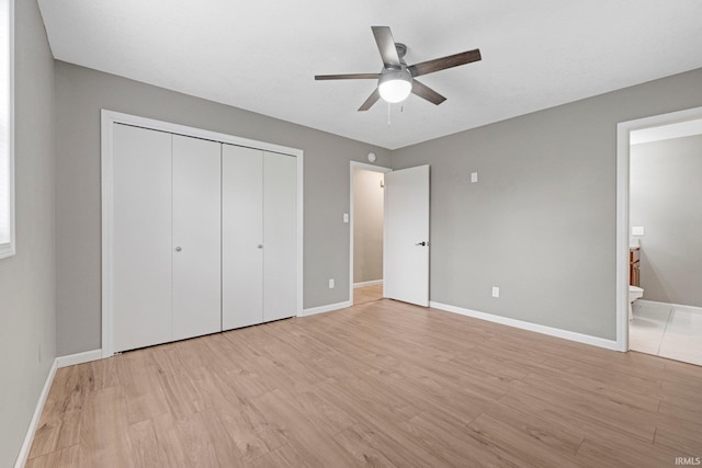 unfurnished bedroom featuring connected bathroom, ceiling fan, light wood finished floors, baseboards, and a closet
