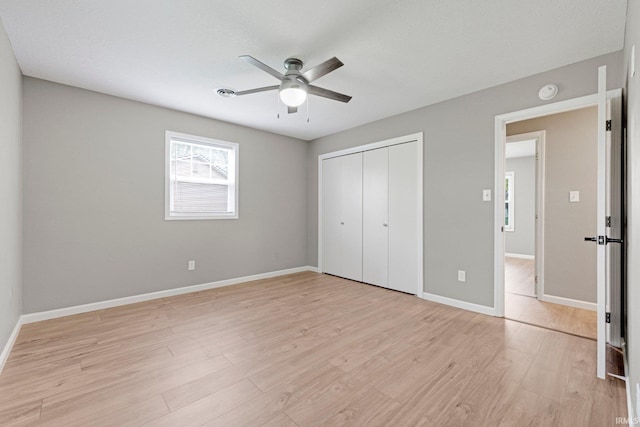 unfurnished bedroom featuring baseboards, ceiling fan, light wood finished floors, and a closet