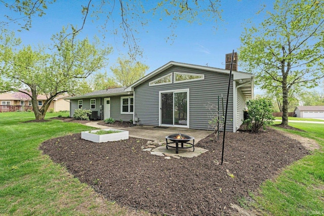 rear view of property featuring a lawn, an outdoor fire pit, a patio area, and a chimney