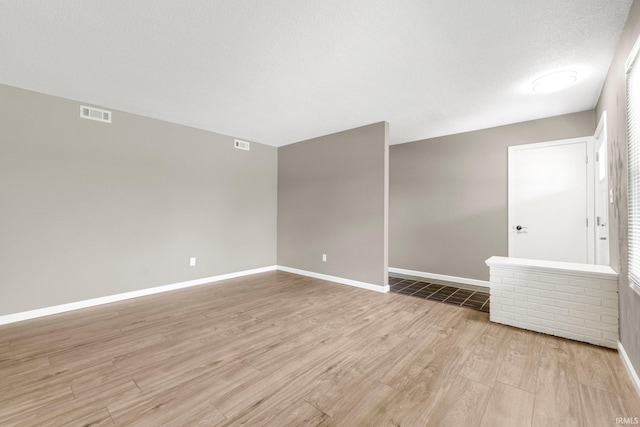 spare room featuring visible vents, light wood-style floors, and baseboards