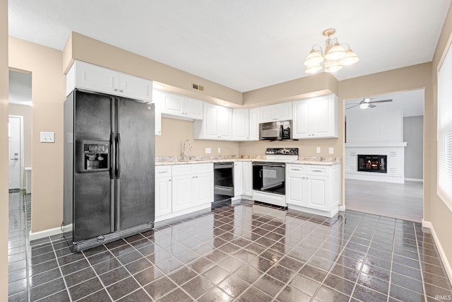 kitchen with baseboards, white cabinetry, dark tile patterned flooring, ceiling fan with notable chandelier, and black appliances