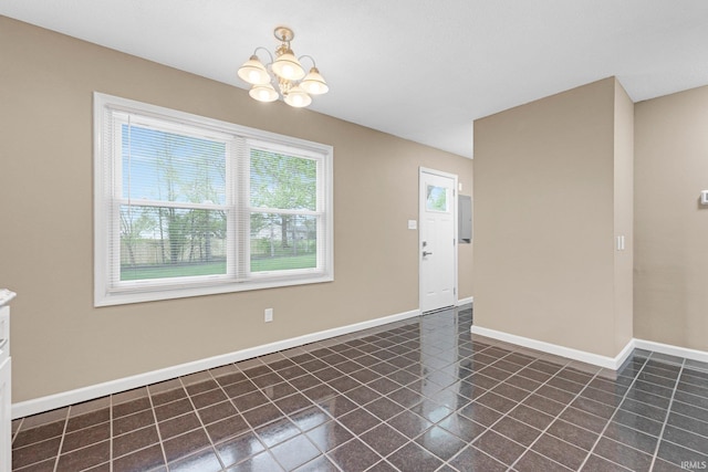 interior space featuring dark tile patterned floors, baseboards, and a chandelier