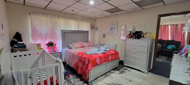 bedroom featuring a drop ceiling and wood finished floors