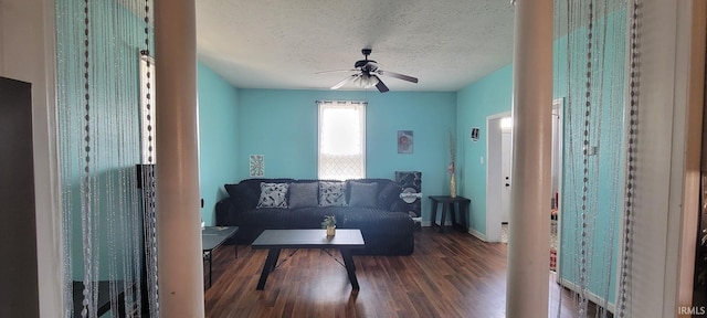living area featuring baseboards, a textured ceiling, ceiling fan, and wood finished floors