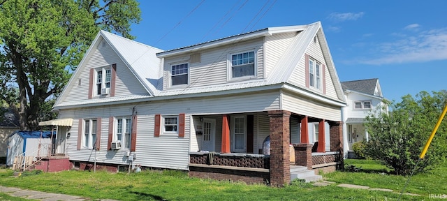 view of front of home with a front yard, a shed, metal roof, a porch, and an outbuilding