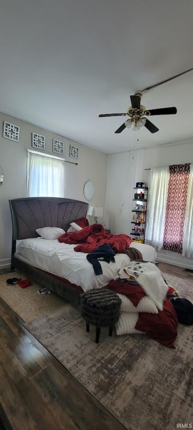 bedroom with a ceiling fan, baseboards, and wood finished floors