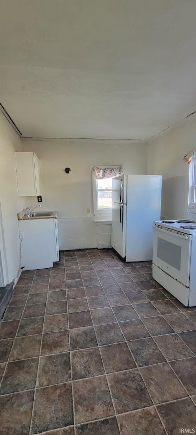 kitchen with white appliances, white cabinetry, and a sink