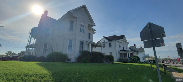 view of side of property featuring a lawn and a chimney