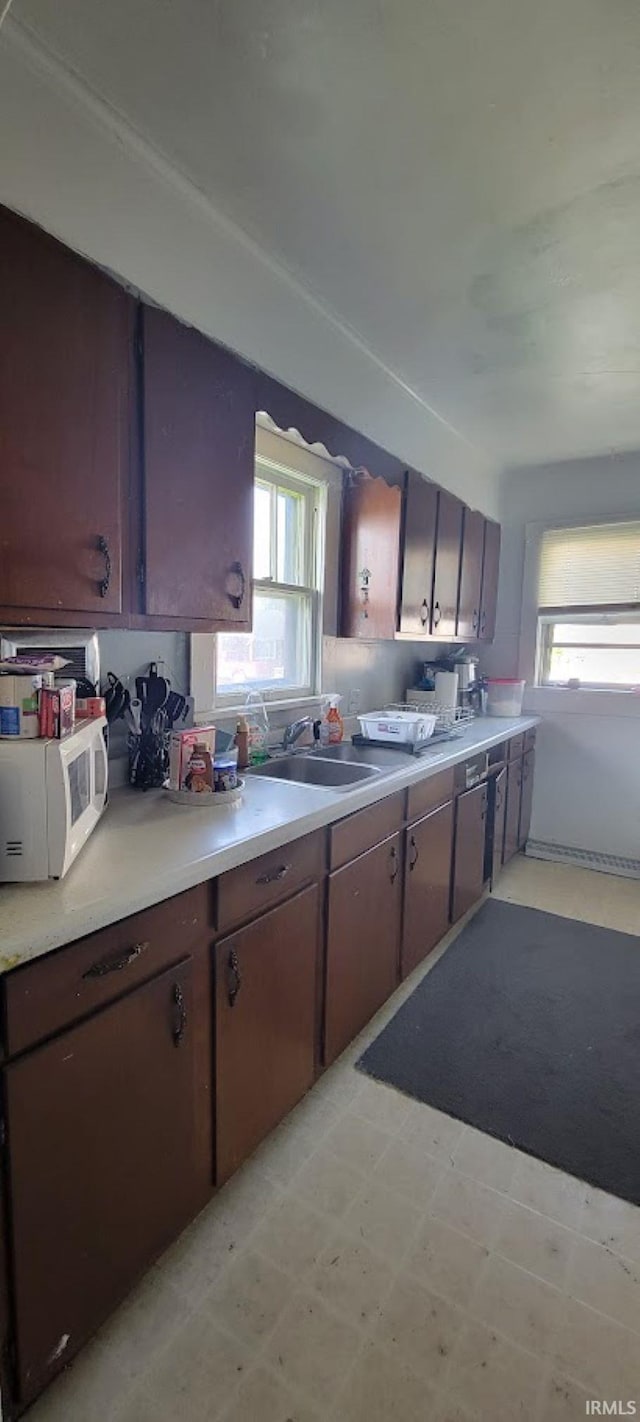 kitchen with plenty of natural light, light countertops, light floors, and white microwave