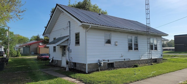 back of property with a lawn, a standing seam roof, and metal roof