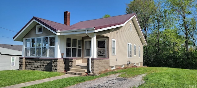 bungalow-style house with metal roof, a front yard, and a chimney