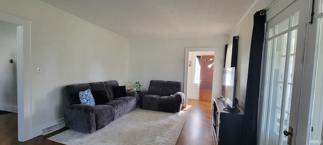 living area featuring visible vents, ornamental molding, and wood finished floors