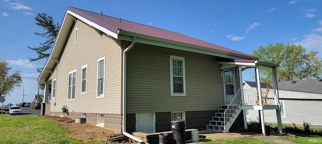 back of property featuring stairs, a lawn, and metal roof