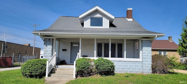 bungalow-style home featuring a porch, fence, and a chimney