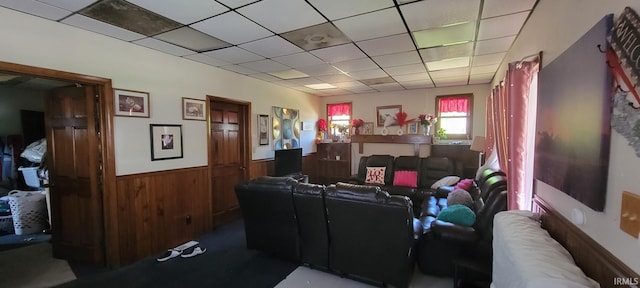 living room with a paneled ceiling, wainscoting, and wooden walls