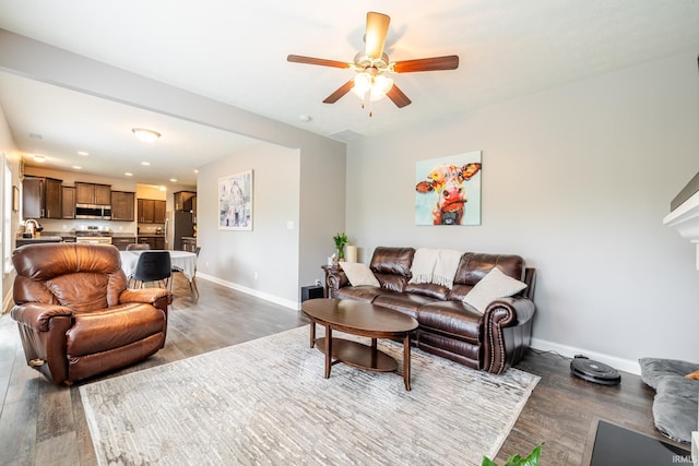 living area featuring baseboards, a ceiling fan, and wood finished floors