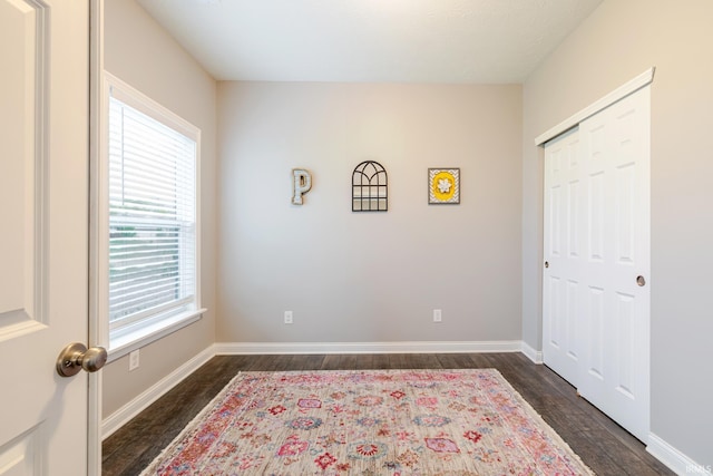 bedroom featuring baseboards, dark wood-style floors, and a closet