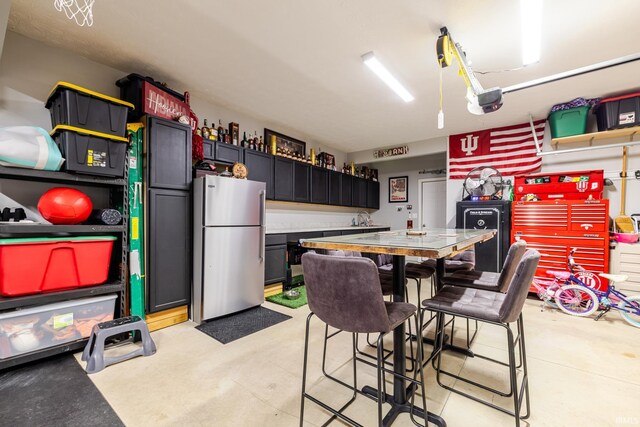 garage with a garage door opener and freestanding refrigerator