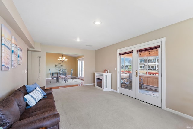 living area featuring light colored carpet, an inviting chandelier, a wealth of natural light, and french doors