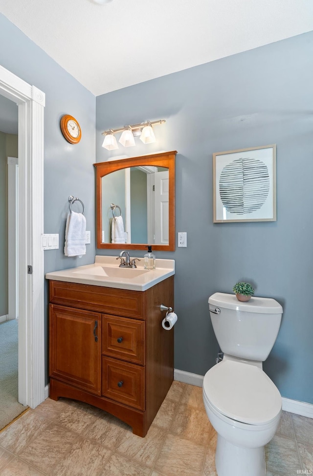 bathroom with toilet, baseboards, and vanity