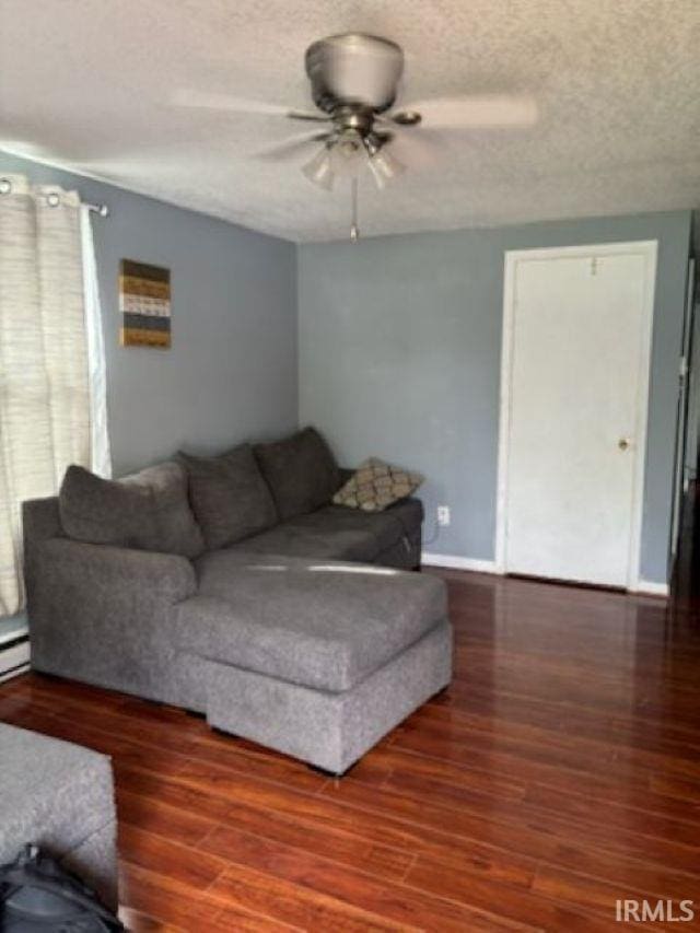 living area featuring a textured ceiling, ceiling fan, baseboards, and wood finished floors