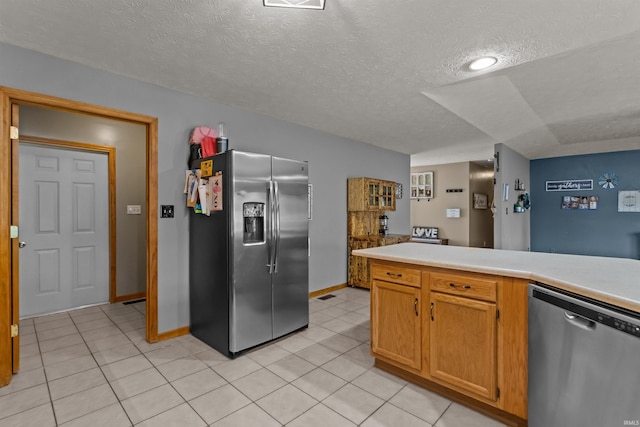 kitchen with light countertops, a textured ceiling, appliances with stainless steel finishes, and light tile patterned floors