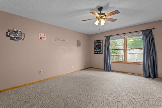 empty room featuring light colored carpet, a ceiling fan, baseboards, and a textured ceiling