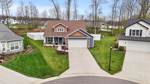 view of front facade featuring a residential view, concrete driveway, a front lawn, and stone siding