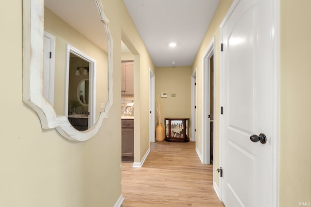 corridor featuring recessed lighting, baseboards, and light wood-type flooring