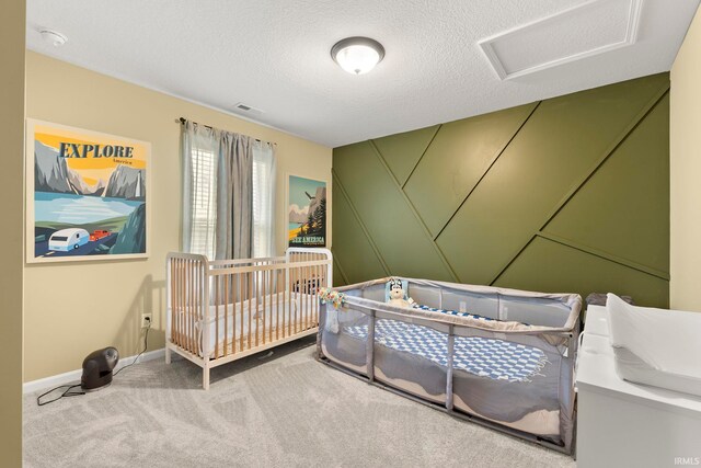 bedroom with carpet floors, a textured ceiling, attic access, baseboards, and visible vents