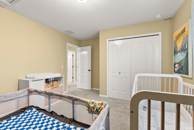 carpeted bedroom with baseboards, a closet, a textured ceiling, and visible vents