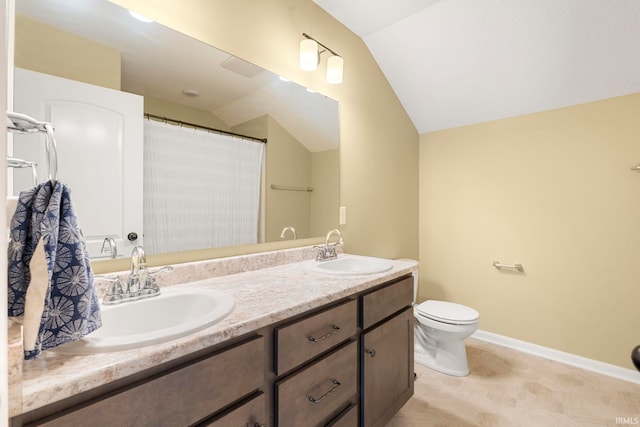 full bath with double vanity, toilet, vaulted ceiling, and a sink