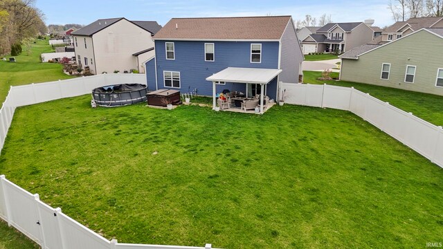 back of property with a patio, a fenced backyard, a lawn, and a residential view
