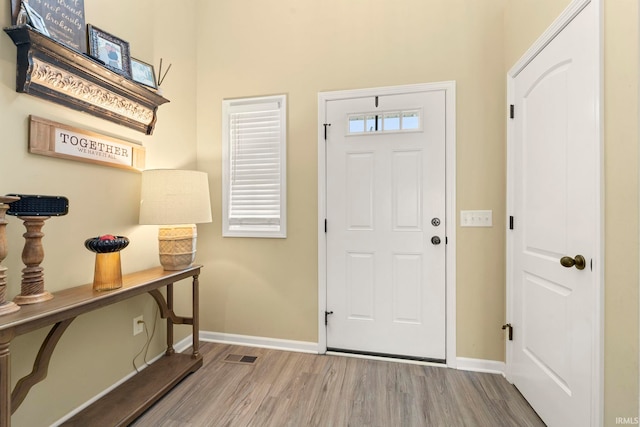 foyer entrance featuring baseboards, wood finished floors, and visible vents