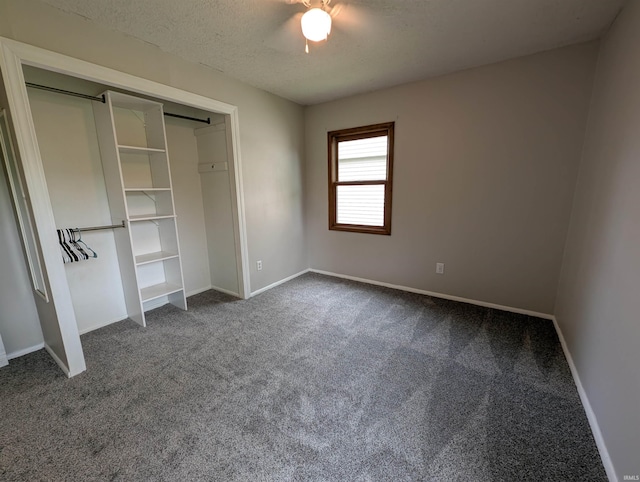 unfurnished bedroom with a textured ceiling, dark colored carpet, a ceiling fan, baseboards, and a closet