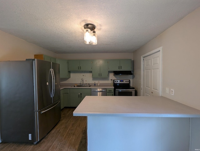 kitchen featuring green cabinetry, a sink, stainless steel appliances, a peninsula, and under cabinet range hood