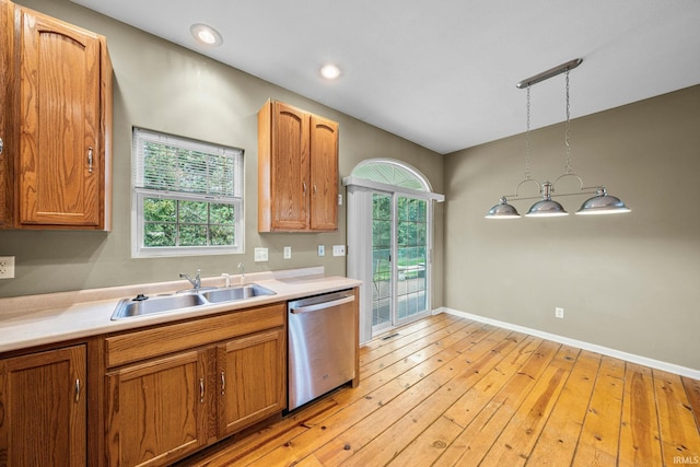 kitchen featuring a sink, light wood-style floors, light countertops, decorative light fixtures, and stainless steel dishwasher