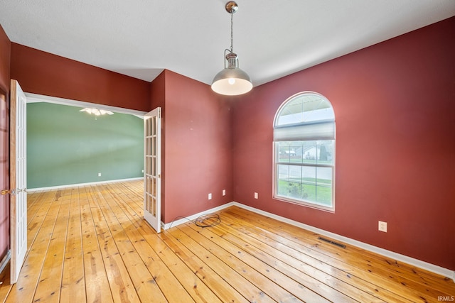 spare room with baseboards, visible vents, and hardwood / wood-style floors