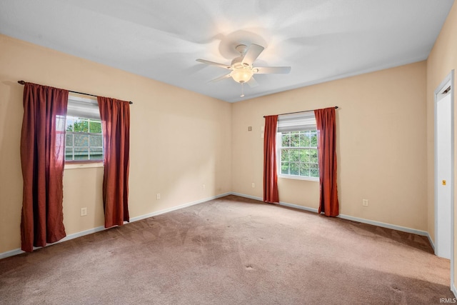 carpeted spare room featuring baseboards and ceiling fan