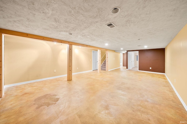 finished basement with a textured ceiling, visible vents, stairway, baseboards, and recessed lighting