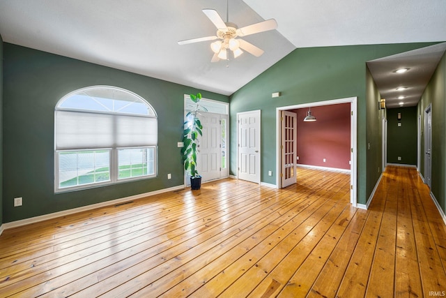 spare room with high vaulted ceiling, baseboards, wood-type flooring, and a ceiling fan