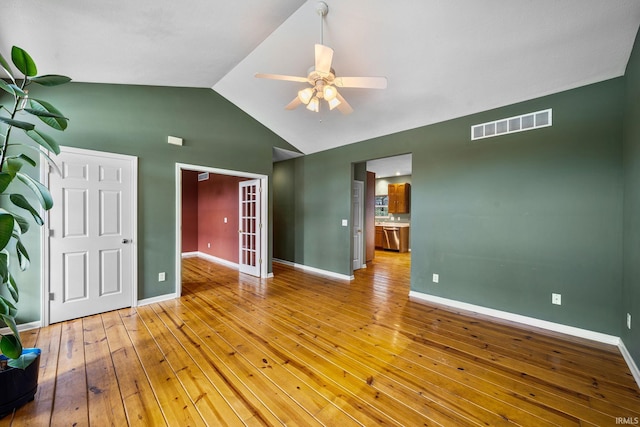 interior space with ceiling fan, visible vents, baseboards, high vaulted ceiling, and hardwood / wood-style floors