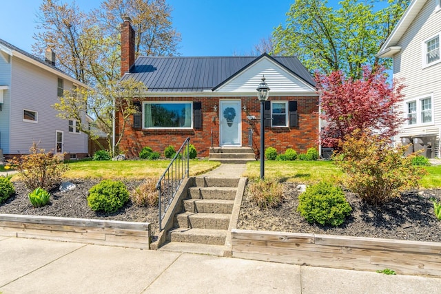 view of front of home featuring brick siding, a chimney, and metal roof