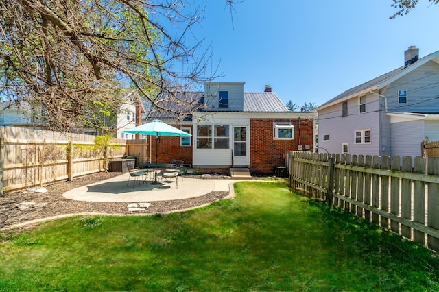 rear view of house featuring brick siding, entry steps, a fenced backyard, a patio area, and a lawn