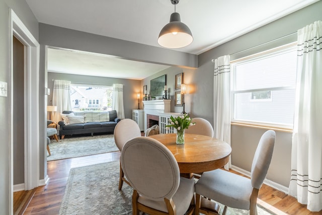 dining room featuring baseboards, wood finished floors, and a fireplace