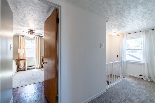 corridor featuring a textured ceiling, an upstairs landing, plenty of natural light, and wood finished floors