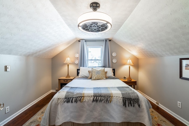 bedroom with baseboards, a textured ceiling, lofted ceiling, and dark wood-style floors