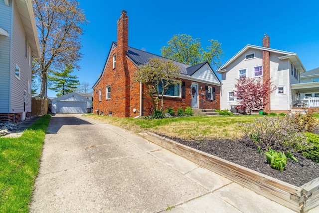 bungalow featuring an outdoor structure, a garage, a front yard, a chimney, and brick siding
