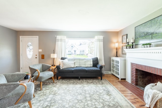 living room featuring a brick fireplace, a wealth of natural light, and wood finished floors